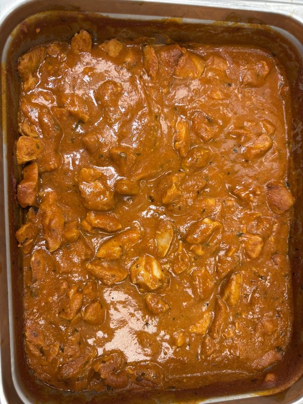A tray of butter chicken in a creamy tomato gravy