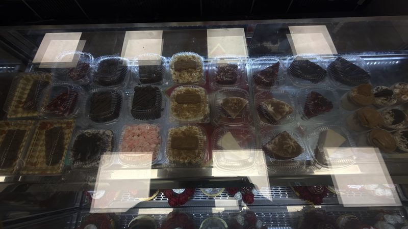 Boxed cake slices and desserts seen through the glass top of the display case