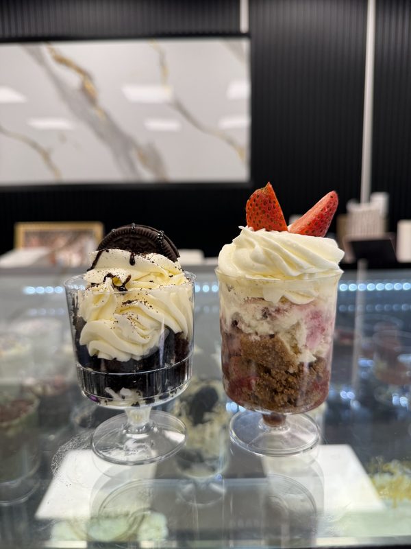 Two layered dessert cups with cream and strawberries in glass goblets