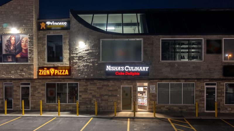 The plaza at night with the lit Nisha's Culinary sign